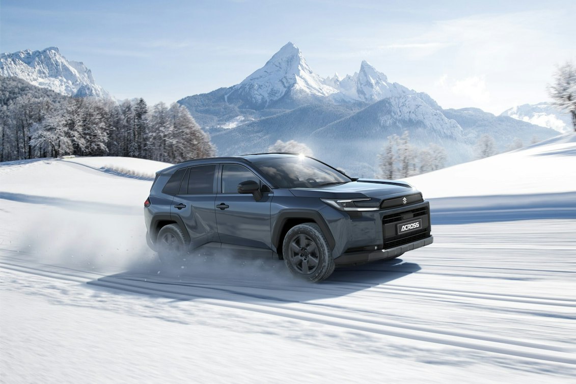 Ein weisser Suzuki Across am Laden, im Hintergrund ein modernes Haus am Meer