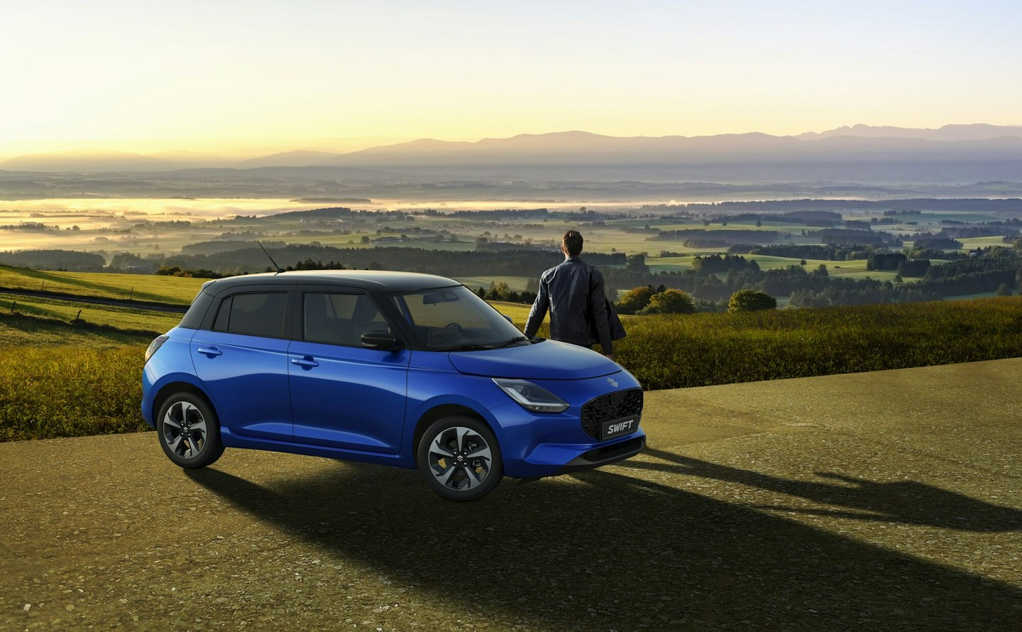 Suzuki Swift und einen Mann, im Hintergrund schöne Landschaft