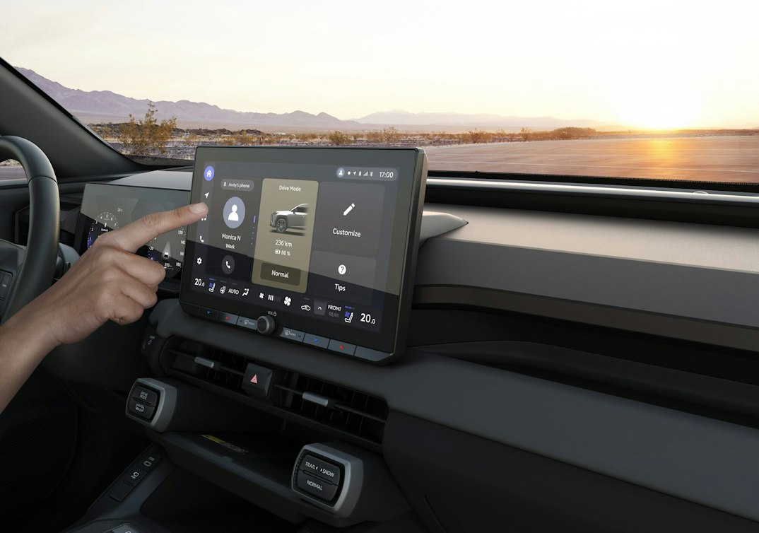 Ein weisser Suzuki Across am Laden, im Hintergrund ein modernes Haus am Meer